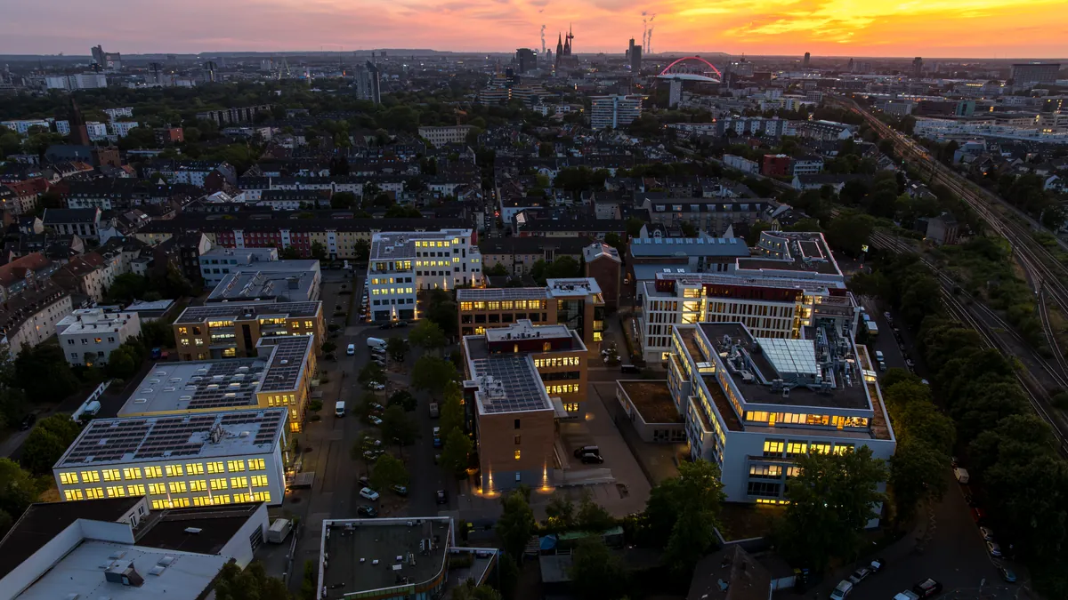 Abendliches Luftbild über Köln-Kalk mit dem Kölner Dom am Horizont – Einsatzgebiet der Gebäudereinigung Wunderlich seit 1986